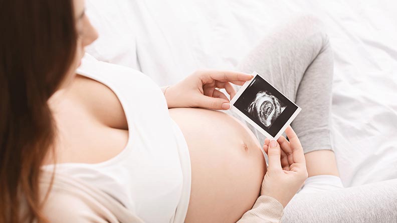 Schwangere Frau sieht sich Ultraschallbild an